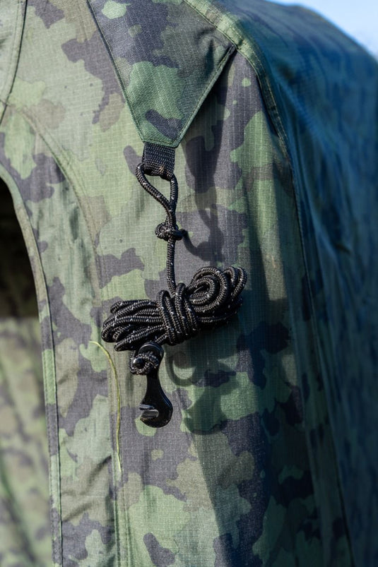 RidgeMonkey Camouflage jacket with a rope and knot accessory on a blurred background