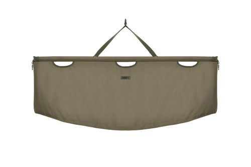 An olive-colored Korda Compac Weigh Sling for fishing, with a hanging loop, quick-release zips, and grab handles.