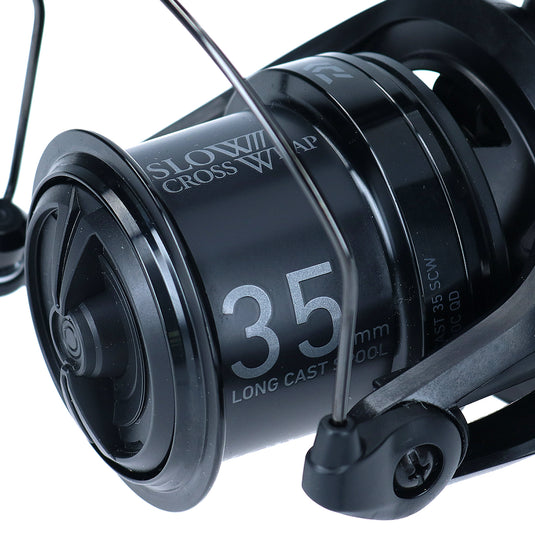 Close-up of a fishing reel with '35 mm' and 'SLOW CROSS W' text on a white background
